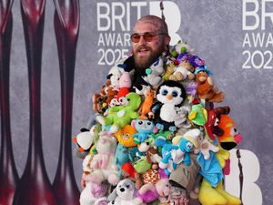 Teddy Swims wearing a coat with stuffed toy animals sewn to it on the Brit Awards red carpet