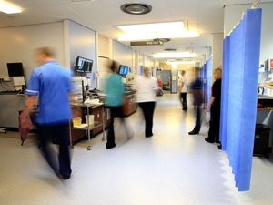 Nurses and doctors walk through a hospital ward