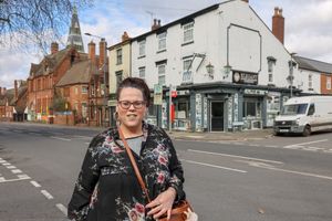 Peaky Blinders fan Louise Swann standing outside a building that used to be the real Garrison pub in Small Heath, Birmingham, and is now Elegant kitchens and bedrooms shop.