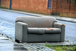 A scruffy sofa is left in a parking space