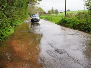 A car drives through water run-off from farmers' fields