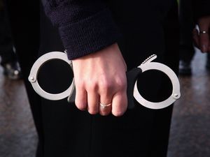 A policeman holds handcuffs