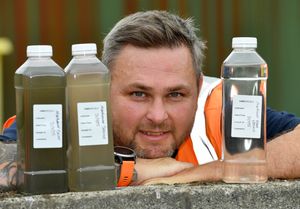 Senior technician Jon-Paul Brown with bottles showing how the wastewater changes through treatment
