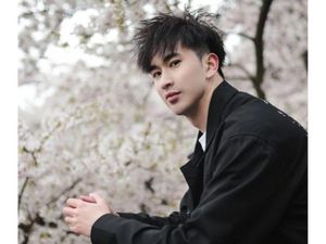 Zhenhao Zou, pictured in front of a tree full of blossom