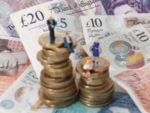 Models of men and women on a pile of coins and bank notes