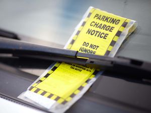 A parking charge notice stuck onto windscreen of a car