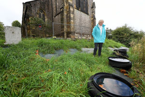 Residents near St John's Church, Dudley, are angry about the state of the cemetery..Judith Fisher next to tyres and tiles, which have been dumped on the graveyard