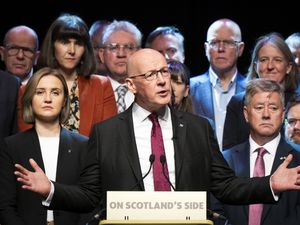 John Swinney with his hands spread as he makes a speech