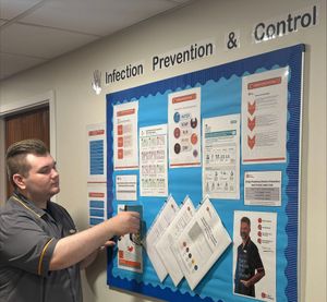 Finn Carragher, Senior Care Assistant at HC-One’s Dingle Meadow Care Home adding information to the Infection, Prevention & Control noticeboard 