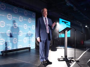 Reform UK leader Nigel Farage on stage with Reform backdrop