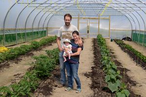 Dave and Daphne Du Cros with baby Isla inside one of the poly-tunnels at Little Woodbatch in Bishop's Castle