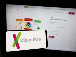 A 23andMe logo on a phone in front of the webpage