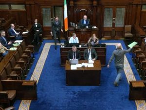 People Before Profit TD Paul Murphy hands Tanaiste Simon Harris a document during Leaders' Questions