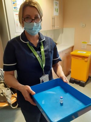 A nurse brings each vial of vaccine to pharmacy colleagues individually, to be drawn up into syringes