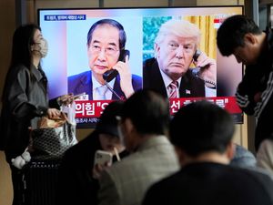 People watch a TV screen showing a file image of South Korean acting President Han Duck-soo and US President Donald Trump, right, during a news programme at the Seoul Railway Station