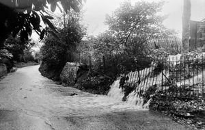 January 16, 1984. The caption reads: 'The source of the problem, a blocked waterway which overflowed its banks into the street.' The story said several roads in the Welsh Walls area of Oswestry were flooded by a torrent of water when a stream became blocked. The source of the problem was a stream at the top of Brynhafod Lane which was blocked by fallen leaves and overflowed its banks into the street.