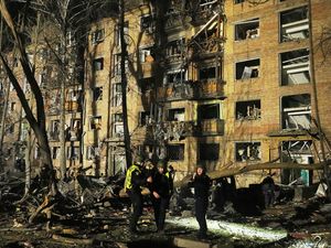 Ukrainian police officers stand near a damaged building after a Russian ballistic missile attack in Kyiv