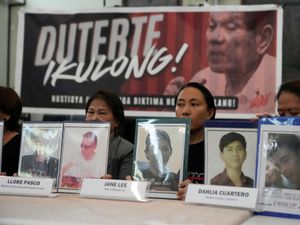 Relatives hold pictures of victims of alleged extra-judicial killings in front of a picture arrested former Philippine president Rodrigo Duterte with a sign that says “Jail Duterte” during a press conference in Quezon City