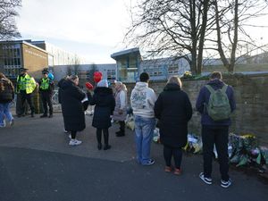 Police officers and floral tributes outside All Saints Catholic High School (PA)