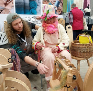 Josh Ogden from Ashford Wheels and Looms helps Katie Summerfield as she tests her spinning skills at Wonderwool Wales