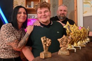Marcia Allen-Shaw and Richard Shaw pose with Ethan as he shows off several of his awards
