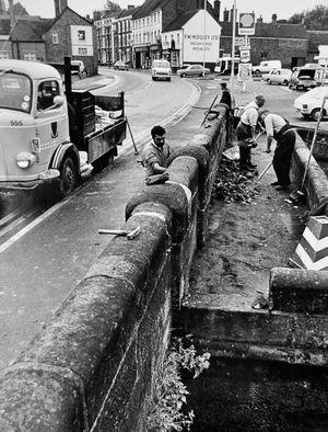 'Salop County Council workers repairing the canal bridge at Newport. The wall was demolished by a car crash last Friday. The bridge is scheduled as an ancient monument and spans the canal over the roving lock, where horses pulling their boats changed sides,' August 14, 1974.