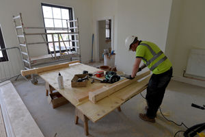 A member of the construction team works to create the period-era bannisters