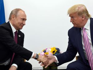 Vladimir Putin shakes hands with Donald Trump in 2019