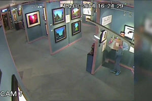 The thief attempts to shove the painting underneath his hoodie.