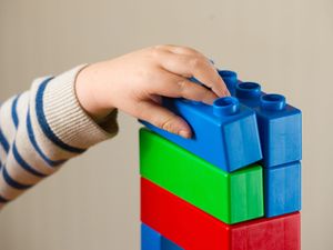 A preschool-aged child playing with plastic building blocks