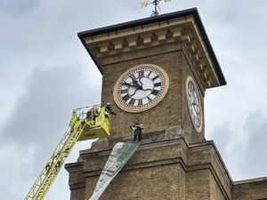 Supporting image for story: Protester clutching a dog climbs clocktower at mainline train station