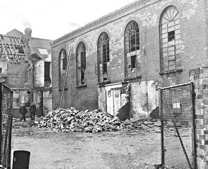The five tall windows of the old Wolverhampton Grammar School in November 1964, with hardly a pane of glass left to be broken, dominate the scene of the desolation.