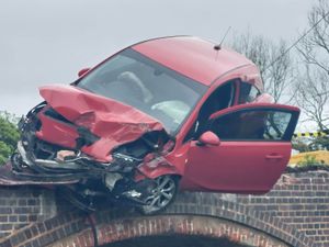 Supporting image for story: Man arrested after car crashes into bridge and left dangling over canal
