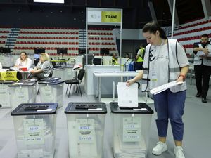 A woman posts ballots into ballot boxes