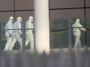 Police forensic investigators walk along a bridge linking Victoria Station with the Manchester Arena
