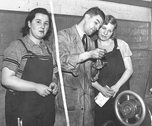 'Mr. K. Thorburn, chief instructor, showing two trainees how to read a micrometer at Walsall Technical College, where women are being trained as munition workers.' February 1941.