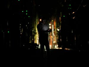 A man checks his mobile phone during a blackout in Jammu