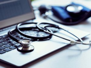 Stethoscope on laptop keyboard in doctor surgery with blood pressure monitor