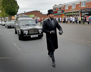 The funeral goes past Mr Bates' shop