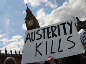 An austerity kills placard held up in front of Big Ben