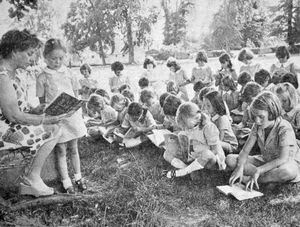 An outdoor lesson for children of Bellan House School, Oswestry, in July, 1976. Class teacher Miss M Jones yesterday took the youngsters into Cae Glas park for a reading lesson. Helping to lead the lesson with Miss Jones is Samantha Shaw.