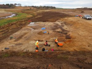 Aerial view of an excavation site, with several people wearing hi-viz