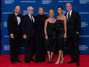 A group of people posing for photos on a red carpet at the White House Correspondents’ Association Dinner