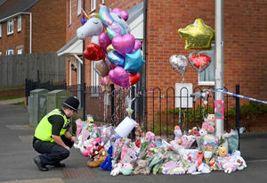 A police officer reads some of the tributes at Robin Close