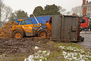 Tractors work to right the trailer and contain the remaining manure