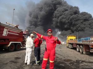Firefighters work as black smoke rises in the sky after a massive explosion rocked a port near the southern city of Bandar Abbas, Iran,