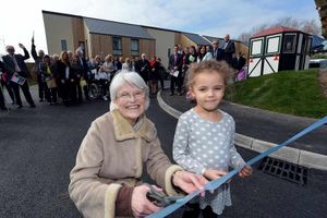 Dennis' widow, Patricia Turner, performs the ribbon cutting with her granddaughter, Bella Mullings