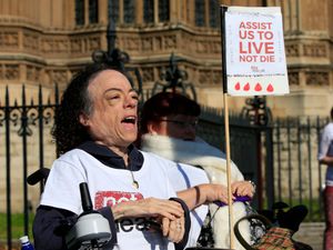 Actress Liz Carr holding a sign reading: 'Assist us to live not die'