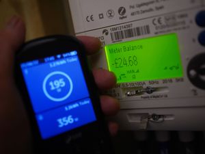 A handheld SSE smart meter for household energy usage is held next to an electricity meter displaying a balance