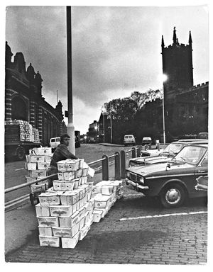 Wholesale Market, Wulfruna Street, Wolverhampton. April 1970. Because Wolverhampton Corporation was not opening the gates until five hours after the produce was delivered, the items were being stolen, trodden, fouled by dogs and gnawed by rodents. The photograph shows the car park by the market with boxes of produce stacked up, and St Peter's Church in the background